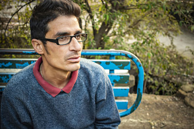 Thoughtful man sitting on bench at park