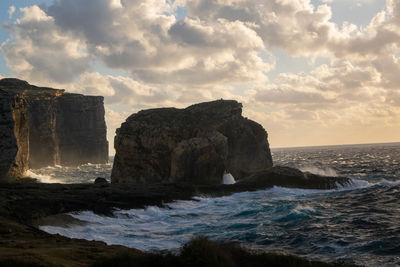 Rock formations by sea against sky