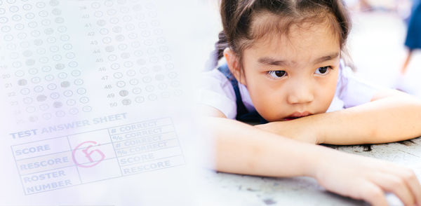 Digital composite image of answer sheet by depressed girl leaning at table