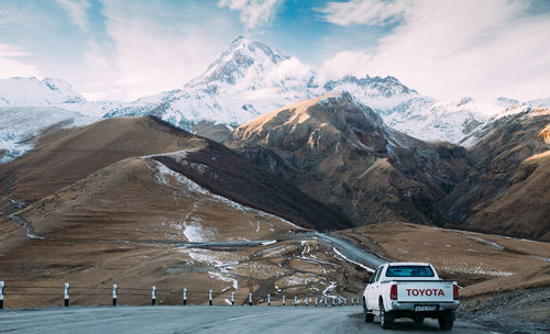 Road amidst snowcapped mountains against sky during winter