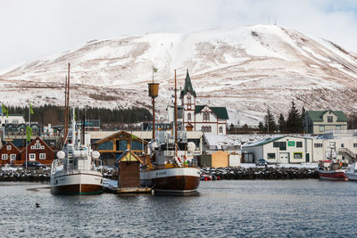 Sailboats on sea by buildings during winter