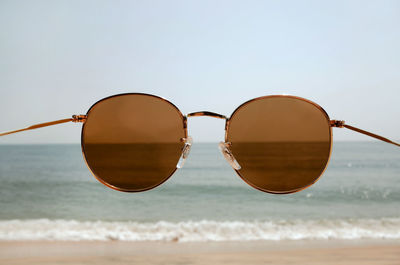 Sunglasses on beach against clear sky