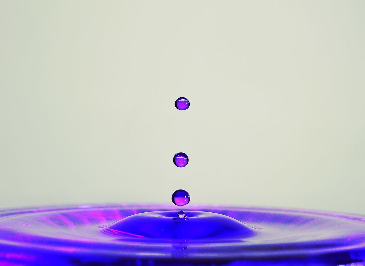 CLOSE-UP OF DROP FALLING ON BLUE WATER