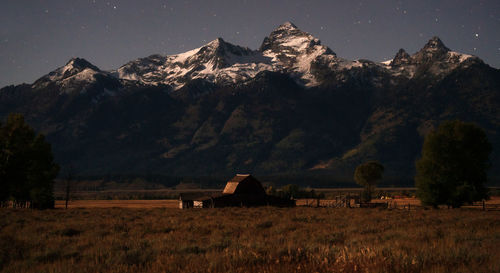 House on field by mountain against sky