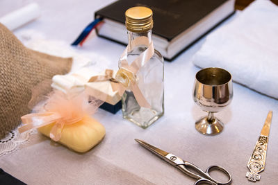 High angle view of glass bottle and scissor on table