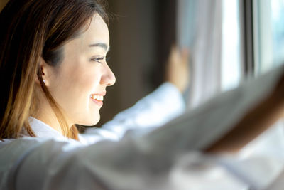 Close-up of young woman looking through window