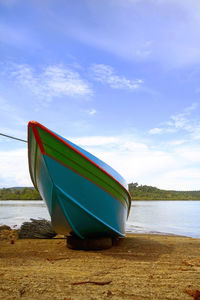 Boat moored on beach against sky