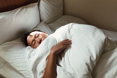 High angle view of man sleeping on bed