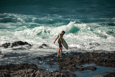 Full length of man standing on rock in sea