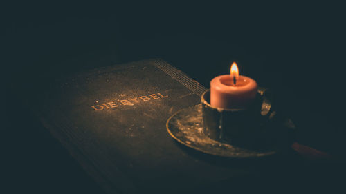 Close-up of lit candle on table against black background