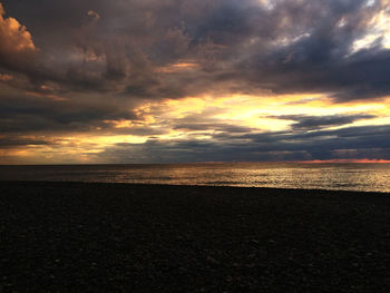 Scenic view of beach against sky at sunset