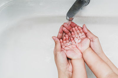 Cropped image of person hand touching water in bathroom