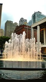 Fountain in city against clear sky