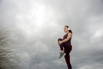 Full length of young woman standing on field against sky