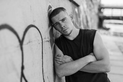 Portrait of young man standing against wall