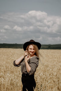 Smiling young woman standing on field against sky