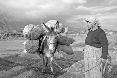 Face covered woman with donkey standing on field