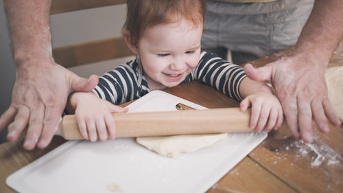 Home made child kid preparing ffod bake with parent help to father