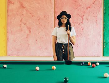 Portrait of young woman holding ball while standing on table