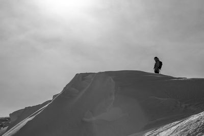 Low angle view of person standing on mountain against sky during sunny day