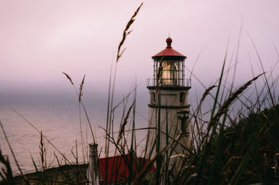 Lighthouse by sea against sky