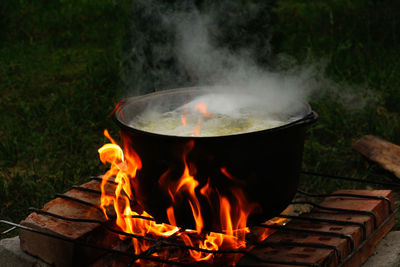 Cooking fish soup in the iron bowler over a campfire. fish soup boils in cauldron at the stake. soup 