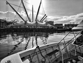 Modern built structure at harbor against sky during sunny day