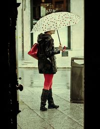 Rear view of woman with umbrella walking in rain