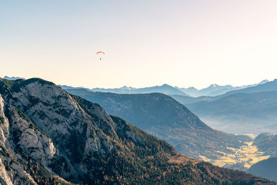 Paragliding pilot flying above mountains in fall colors, altaussee, austria.
