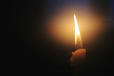 Close-up of lit candle against black background