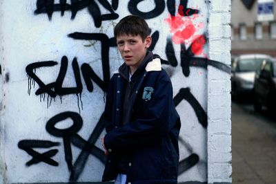 Portrait of boy standing against graffiti wall