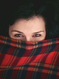 Close-up portrait of woman covering face with blanket