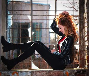 Side view of young woman sitting on old window sill