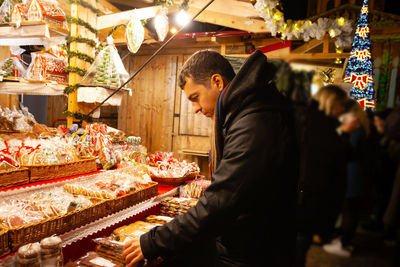 Man looking at illuminated market stall
