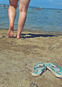 Low section of woman at beach on sunny day