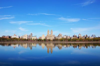 Reflection of buildings in lake against cloudy sky