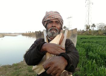 A farmer is going home after completing his routine work at farms with his tools.