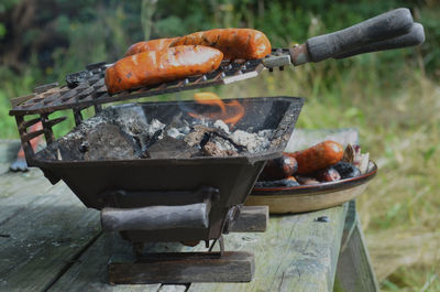 Italian sausages with grill marks on hibachi tabletop grill outdoors on picnic table