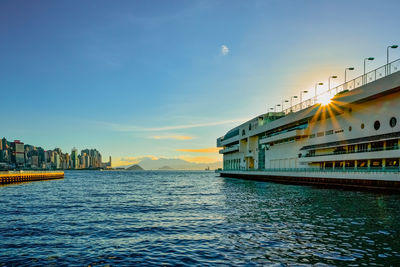 Scenic view of sea by buildings against sky during sunset