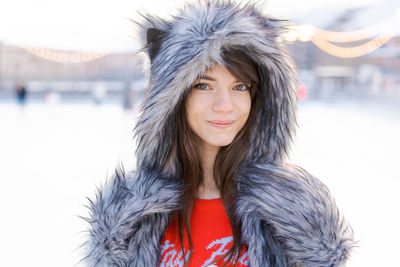 Portrait cute young woman in shaggy hat with ears looks at camera and smiles