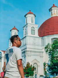 Low angle view of man standing by building against sky