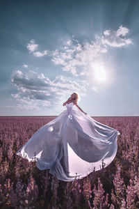 Woman with umbrella on field against sky