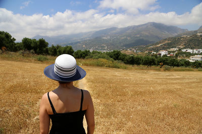 Rear view of woman standing on field against sky