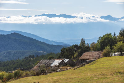 Scenic view of field by houses against sky