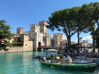 Boats in canal amidst buildings against clear blue sky