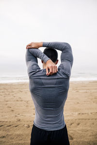 Sportive young man stretching on the beach