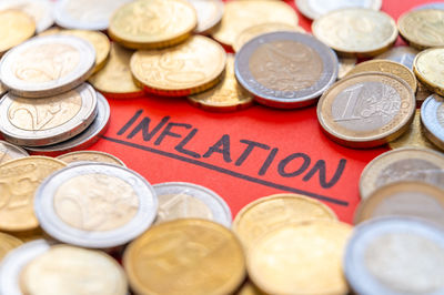 Word inflation on red surface, surrounded by euro coins. rising prices and economic repercussions.