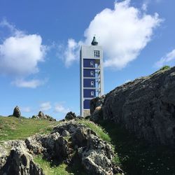 Low angle view of lighthouse by buildings against sky