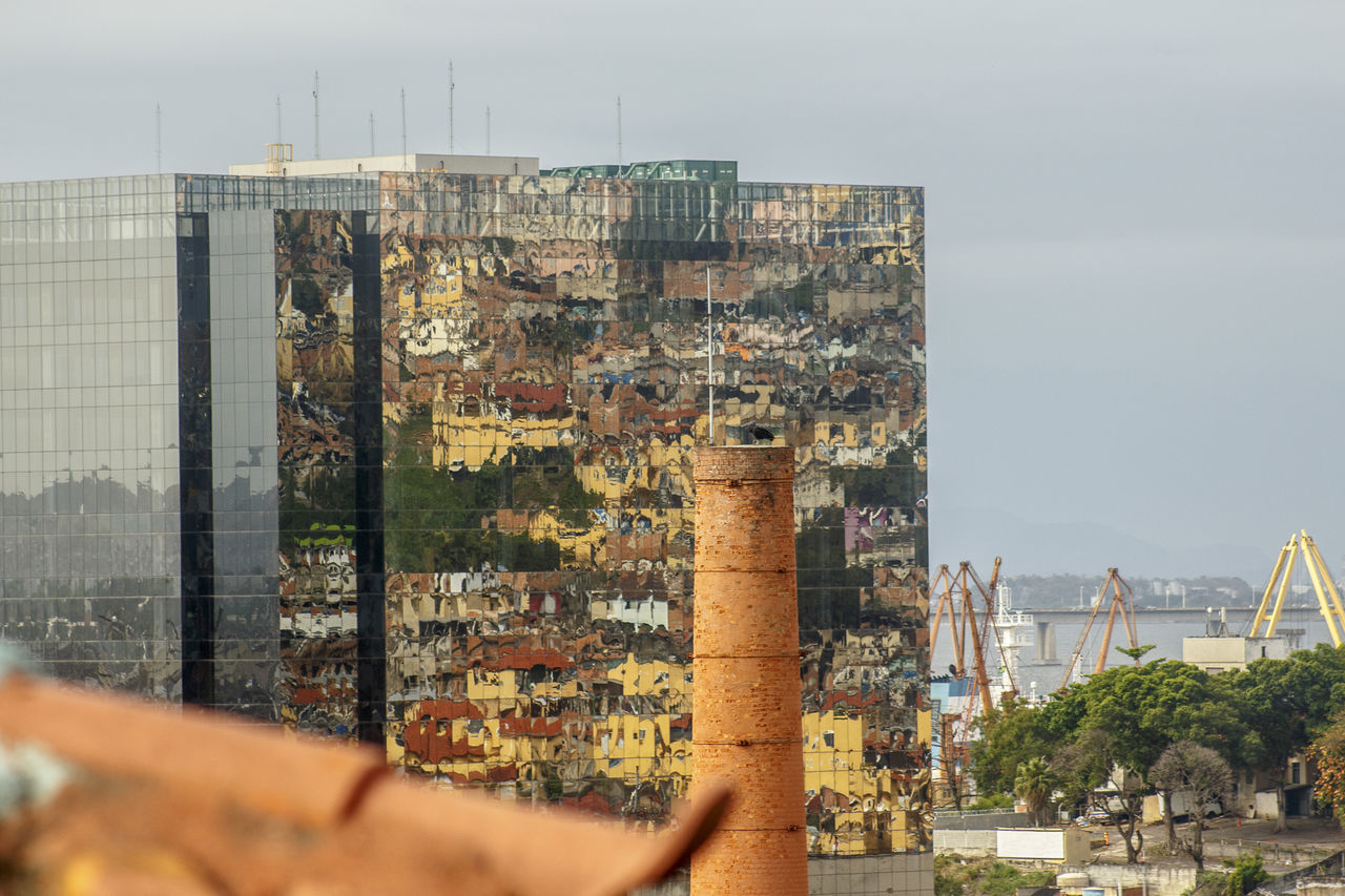 MAN PHOTOGRAPHING CITYSCAPE AGAINST SKY