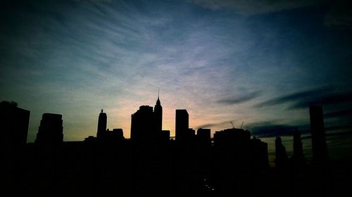 Silhouette of buildings against cloudy sky at sunset